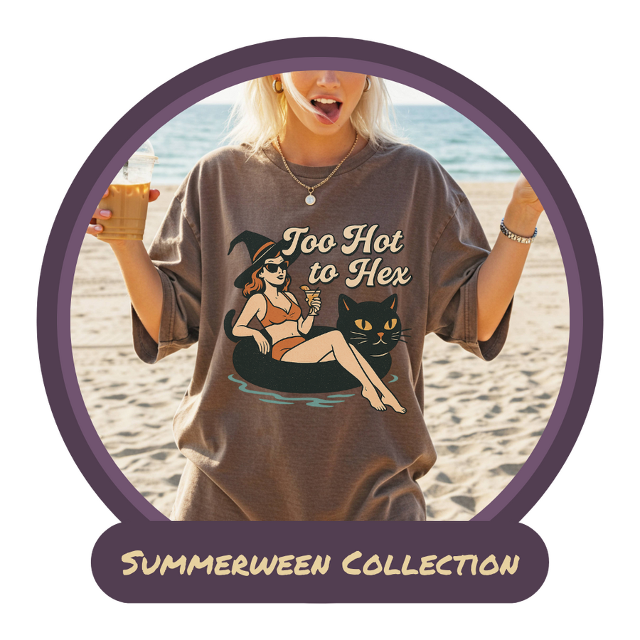 blonde woman on the beach holding an iced coffee in one hand and displaying a peace sign with the other, wearing an espresso colored t-shirt with a witch in a bikini on a black-cat pool floatie with the words "Too Hot to Hex"
